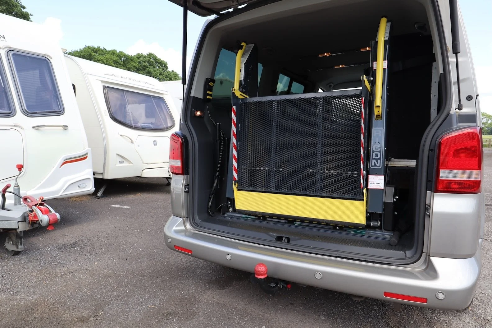 Volkswagen Transporter wheelchair accessible vehicle with the boot open showing a hydraulic wheelchair lift and a detachable towbar below