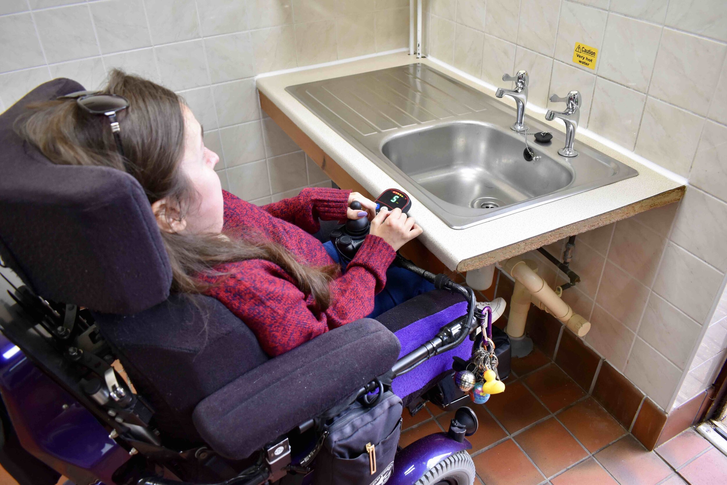 A wheelchair user at a lowered washing up sink at Black Horse Farm Caravan and Motorhome Club Site.