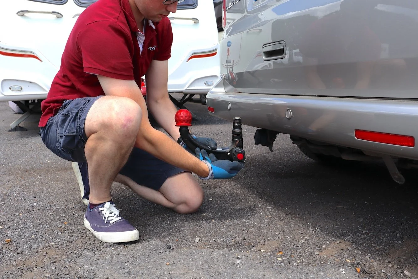  Stephen is holding a detachable towbar in the process of attaching it to the rear of a wheelchair accessible Volkswagen Transporter 