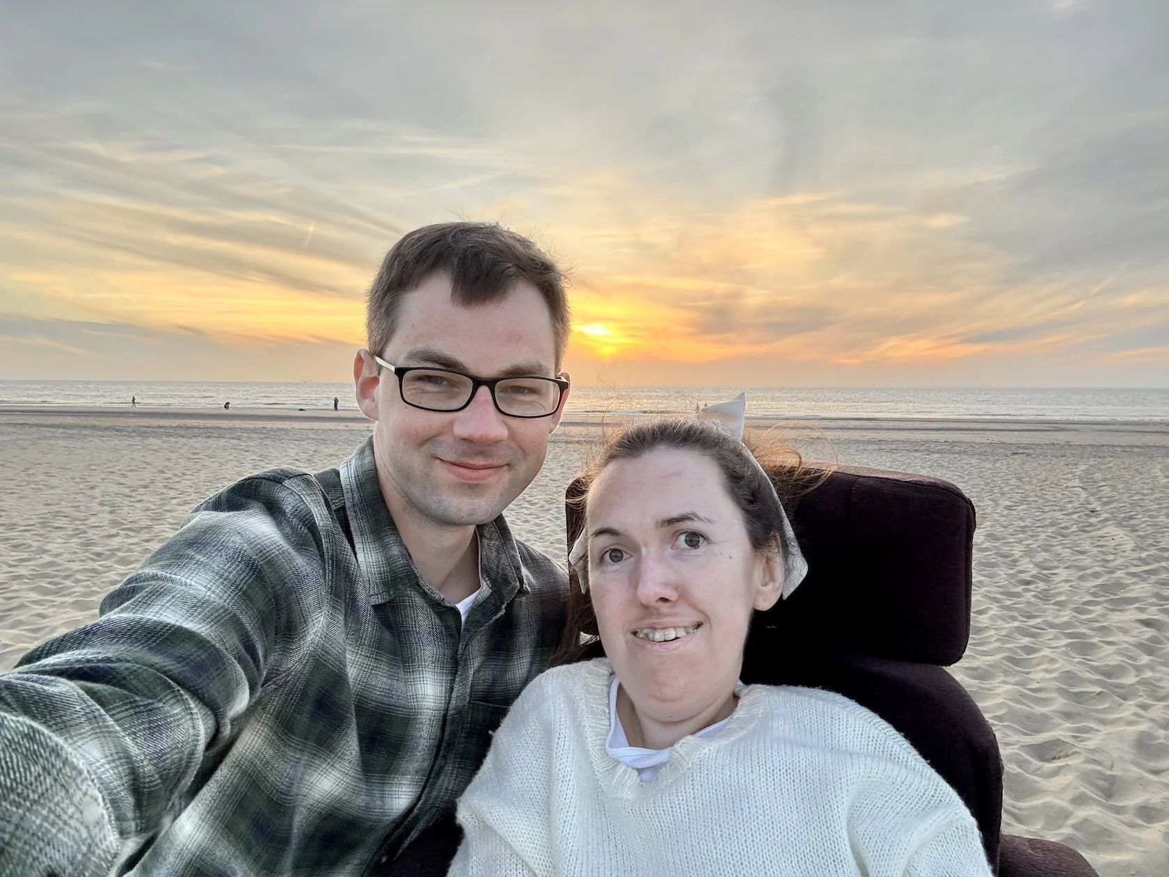  Karla and Stephen on a wheelchair accessible beach at Katwijk aan Zee in the Netherlands. A sunset is behind them 