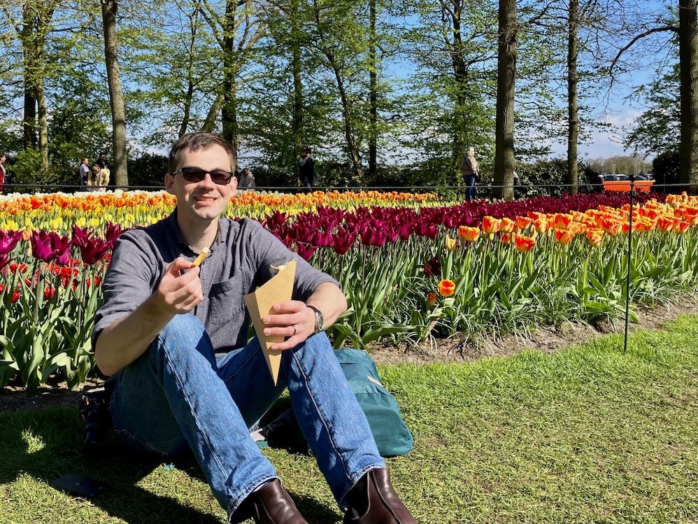  Stephen eating frites at Keukenhof gardens in the Netherlands, surrounded by tulips 