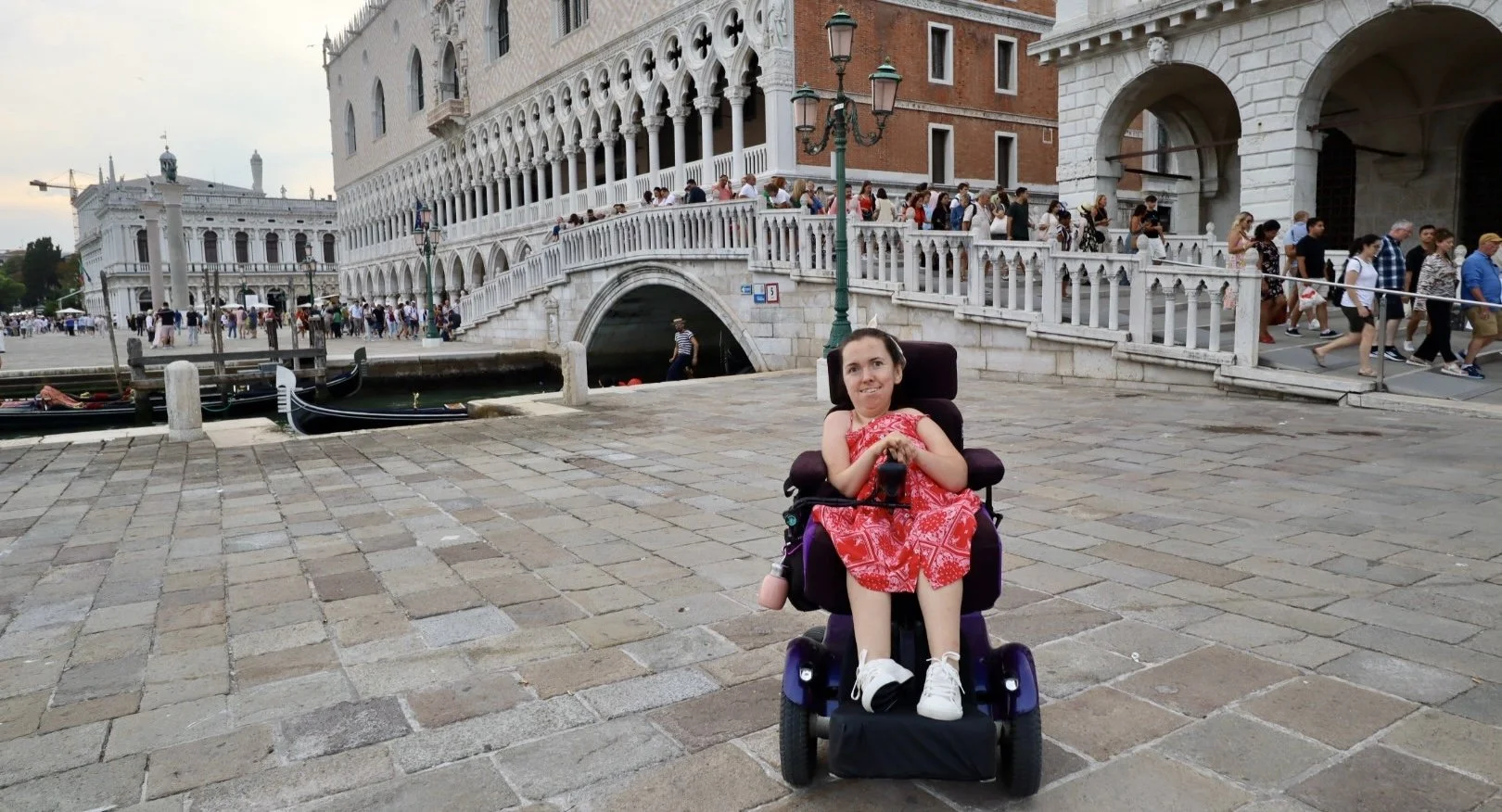 Karla, wearing a red dress and sitting in her powerchair, demonstrating the wheelchair accessibility of Venice