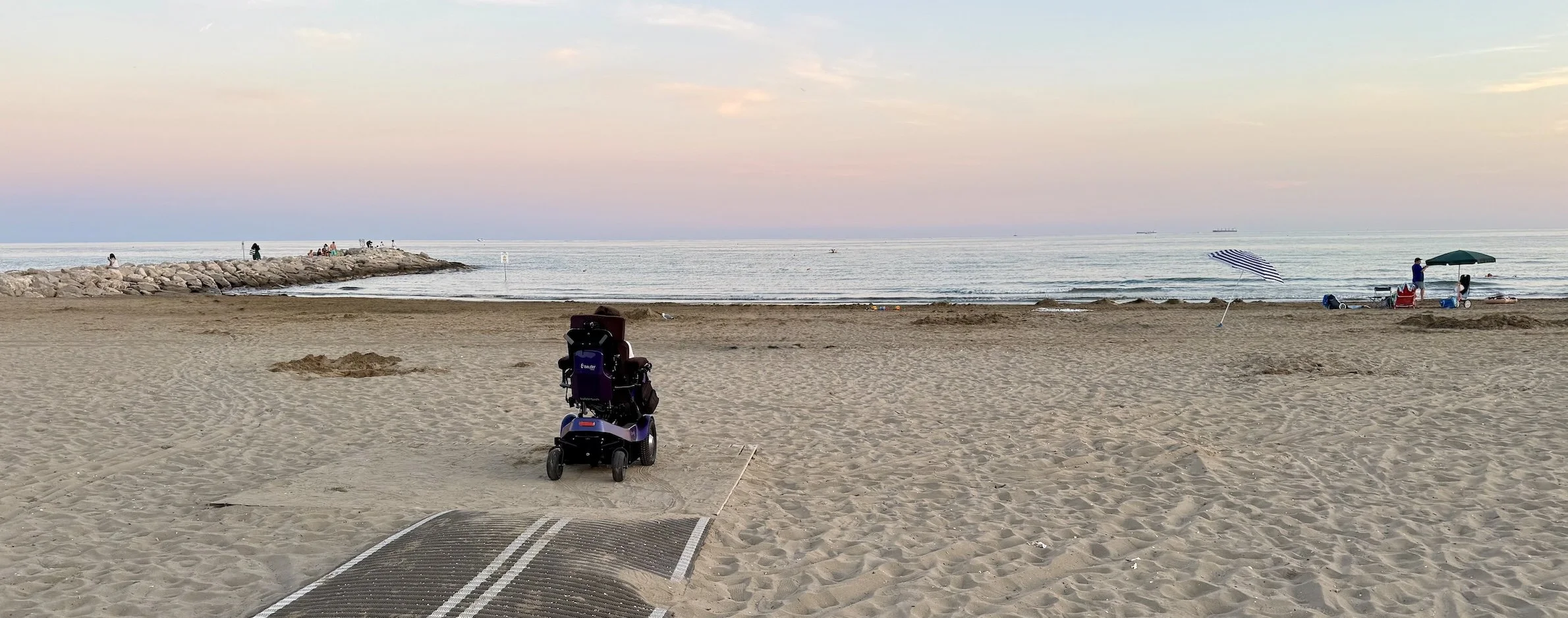 Sunset at the beach at Camping Ca' Savio. Karla is sitting on a path in her wheelchair, looking out to sea