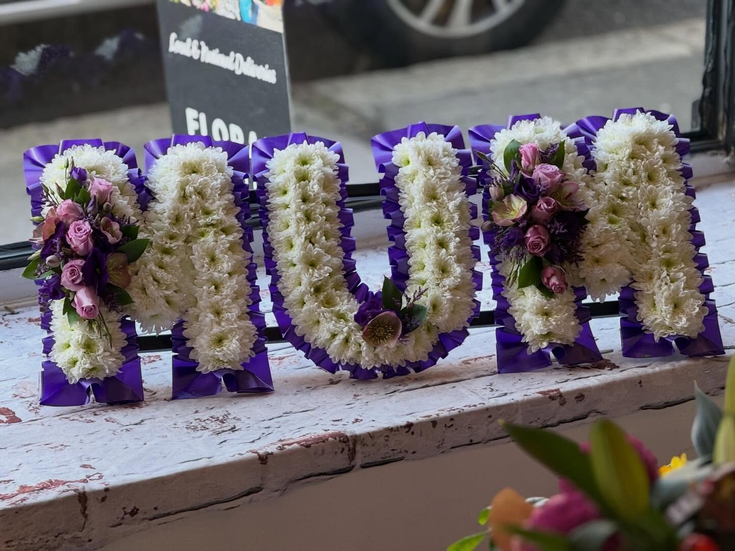 A stunning &ldquo;MUM&rdquo; funeral tribute created with care and attention to every detail 💜

This design features crisp white chrysanthemums, beautifully finished with bold purple edging and elegant purple sprays &mdash; a striking and meaningful