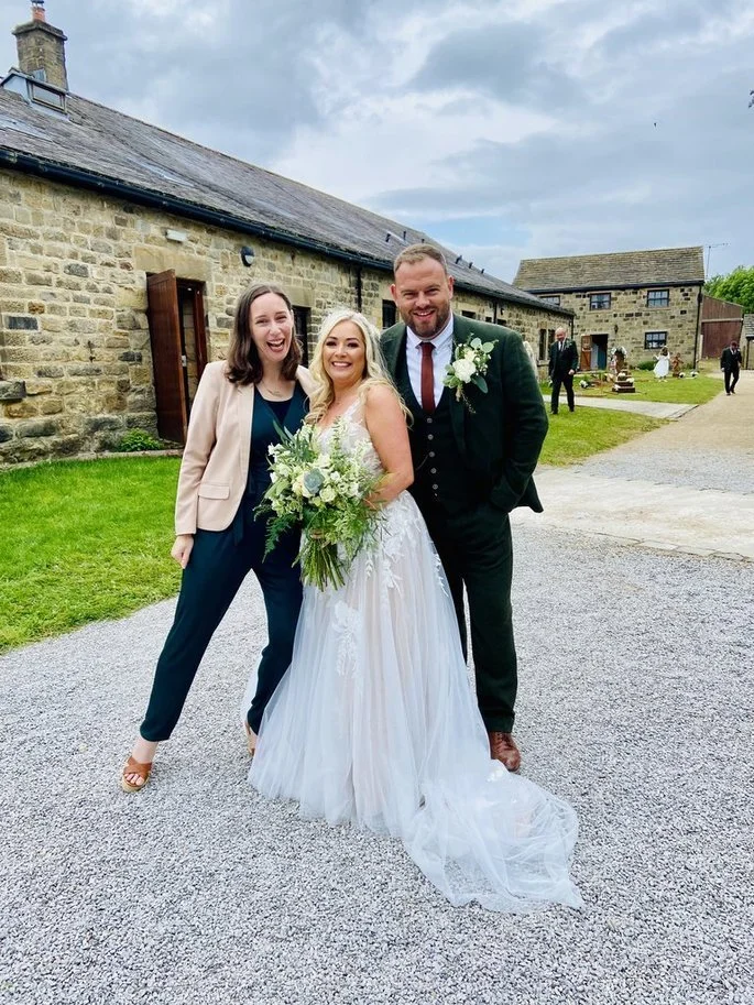 A bride, groom and their wedding celebrant smiling after a beautiful rustic outdoor non-religious wedding ceremony.