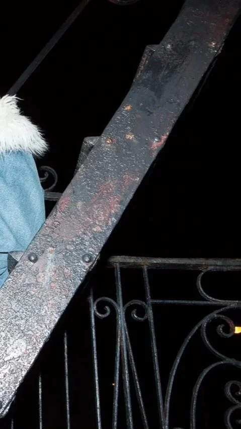 a textural detail of a Brooklyn fire escape railing and the soft fur of a denim jacket lined with white faux fur photo taken at night with flash