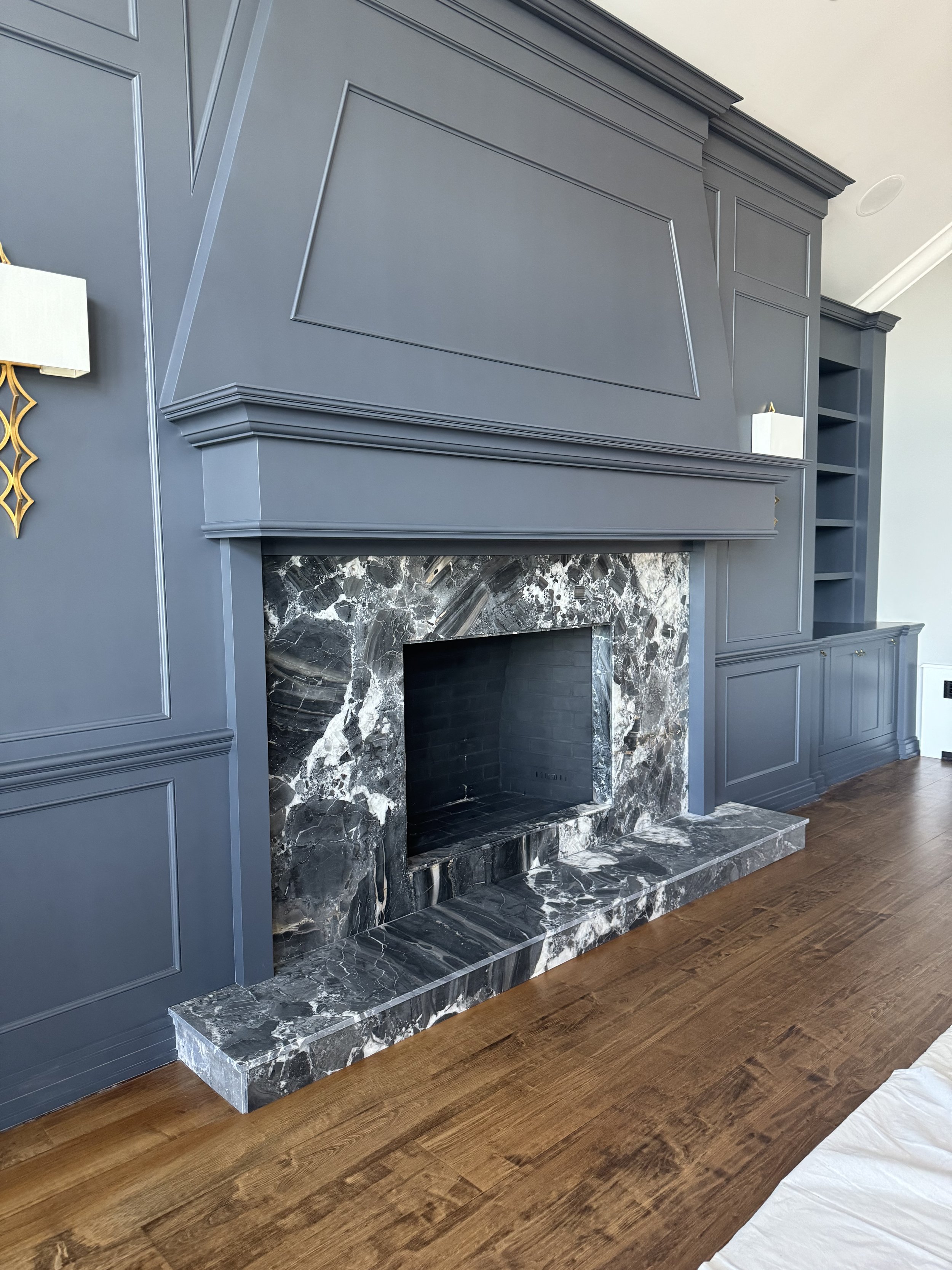 Dolomiti fireplace with custom step-up hearth. Marble with bold grey and white veining. Blue moldings and mantel with hardwood floors. Manhasset, NY.