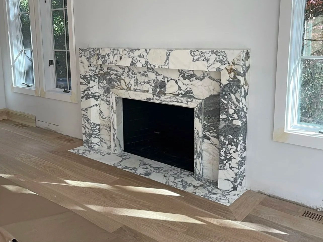 Statuarario marble fireplace custom mitered against a clean white wall and wooden floors in Manhasset, New York. 