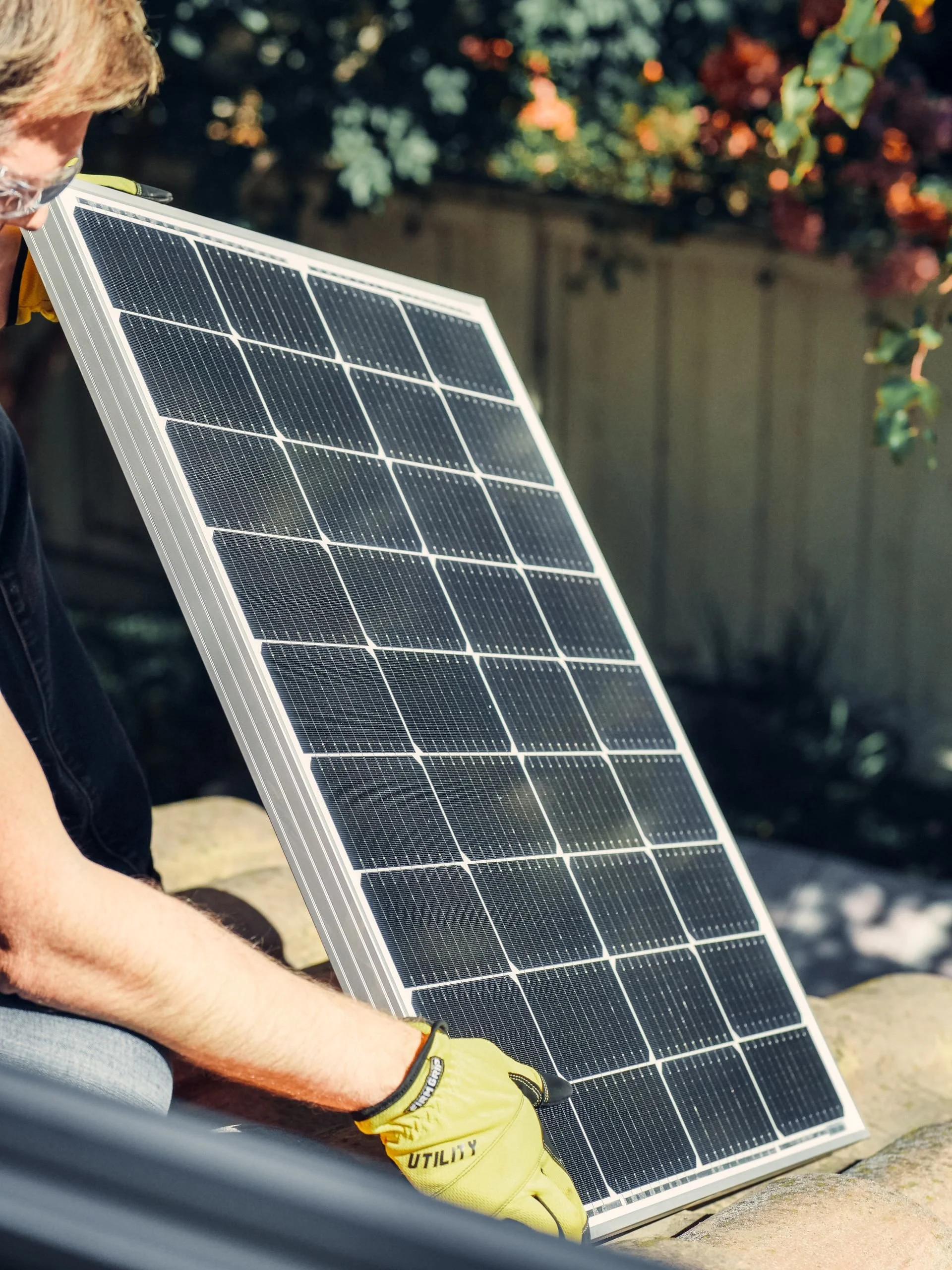 Fachmann hält ein Photovoltaikmodul, um eine Solaranlage auf einem Garagendach zu montieren