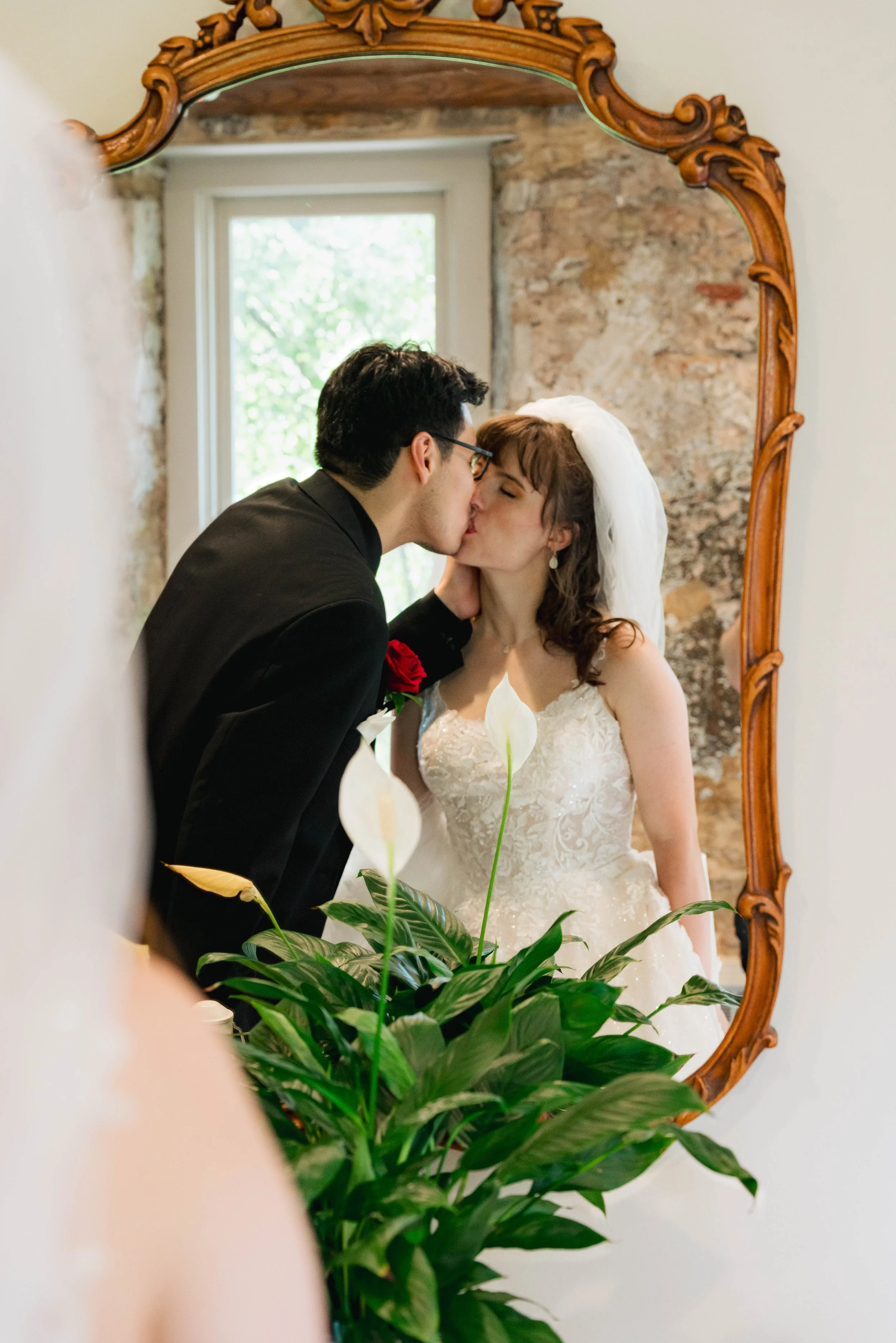 A bride and groom kissing in front of a mirror