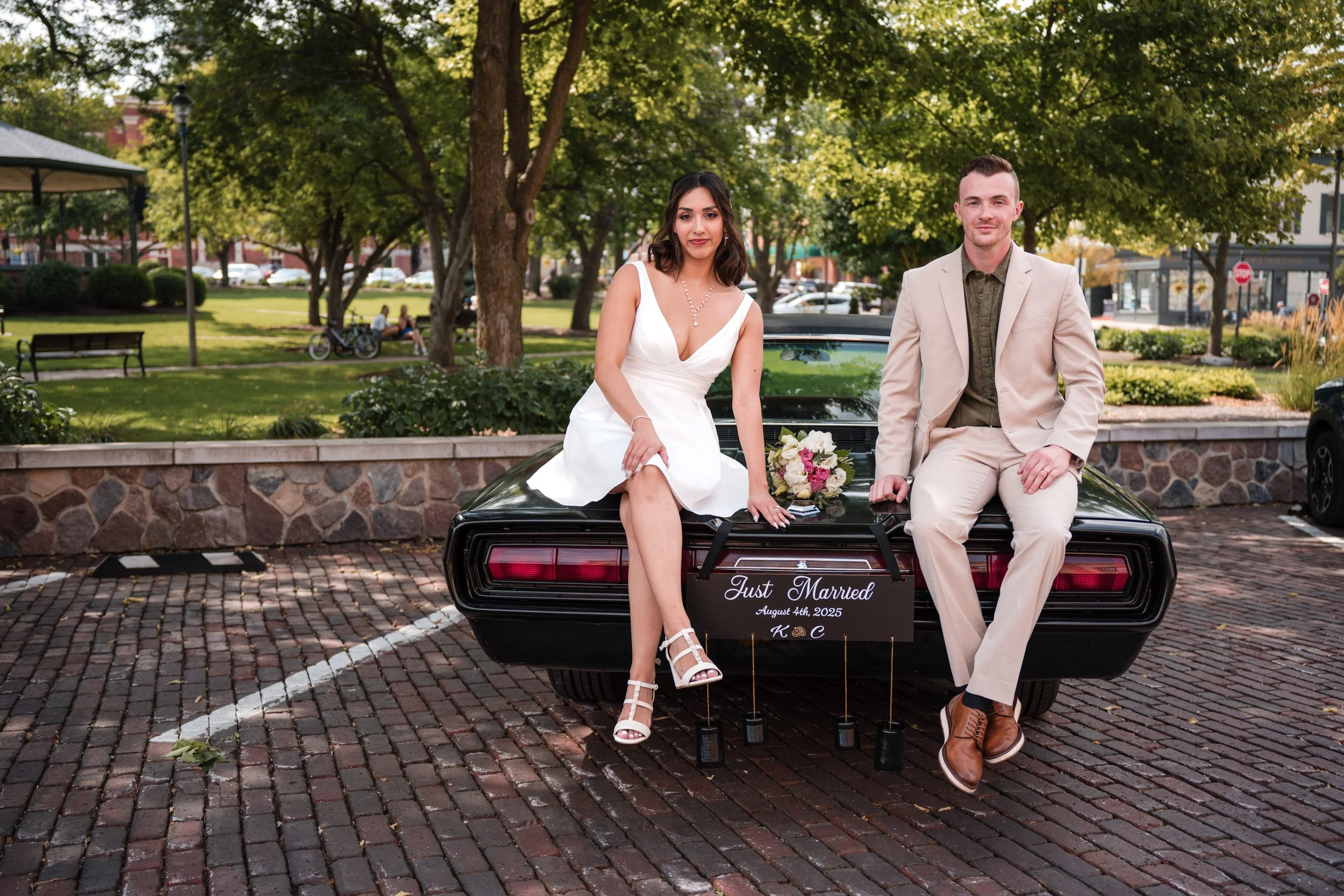 A bride and groom sitting on the back of a car