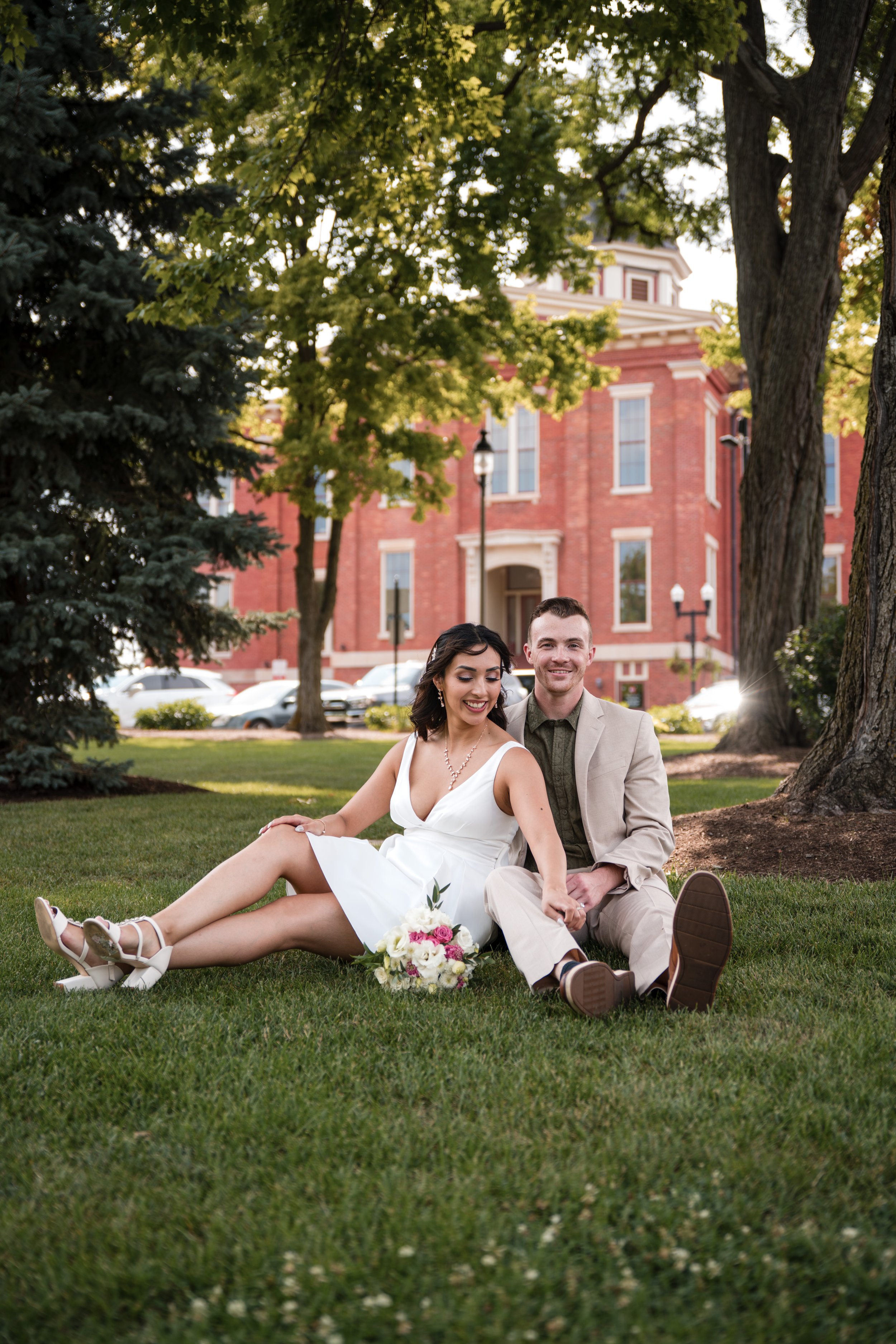 A bride and groom sitting in a park