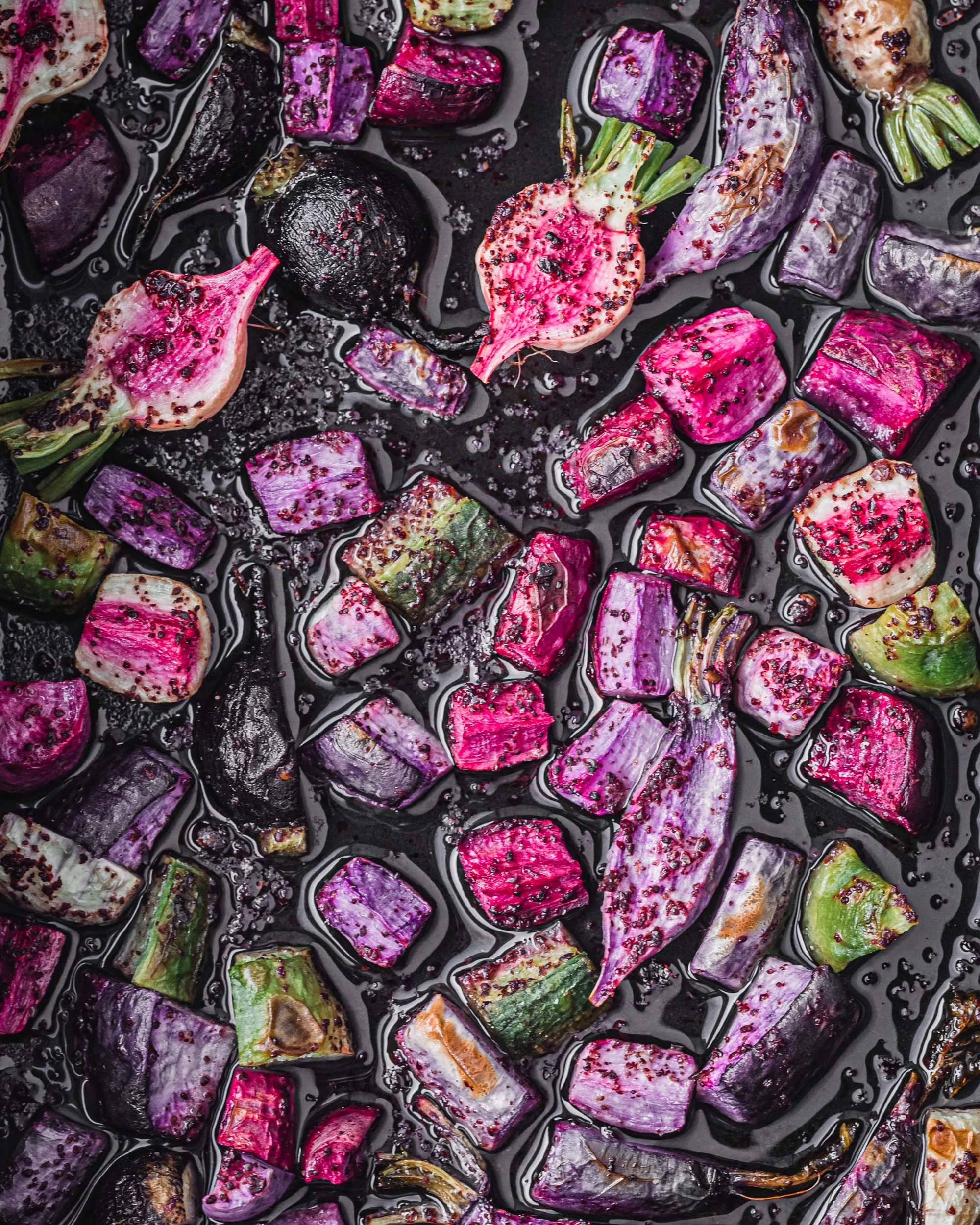 colorful roasted radishes with sumac in a tray with olive oil. Pink, purple and green radishes. 
