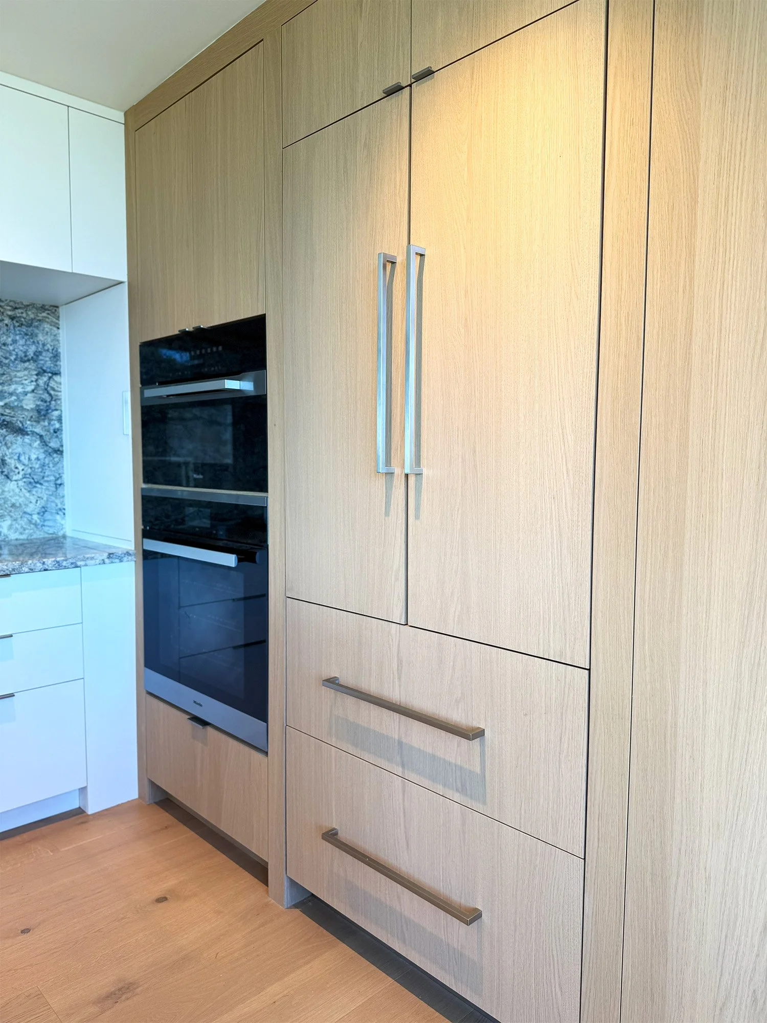 Kitchen with white oak cabinetry and built-in oven wall in San Carlos