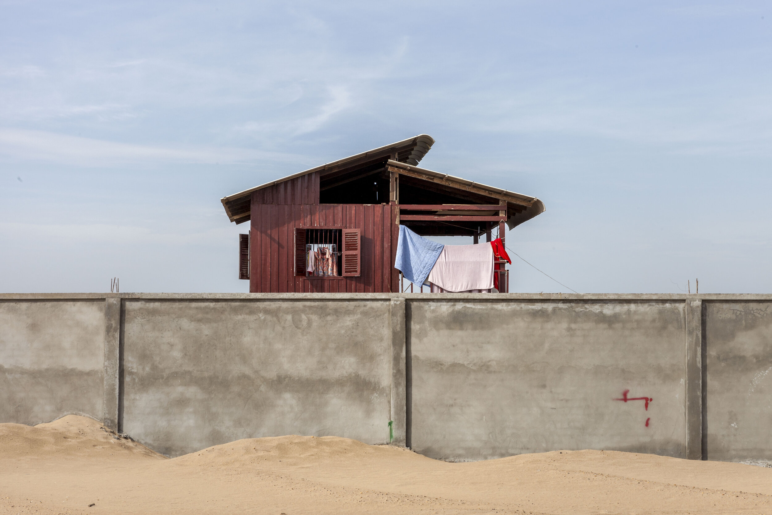  A concrete wall at the edge of the current sand landfill, with a Prek Takong home on the other side.    