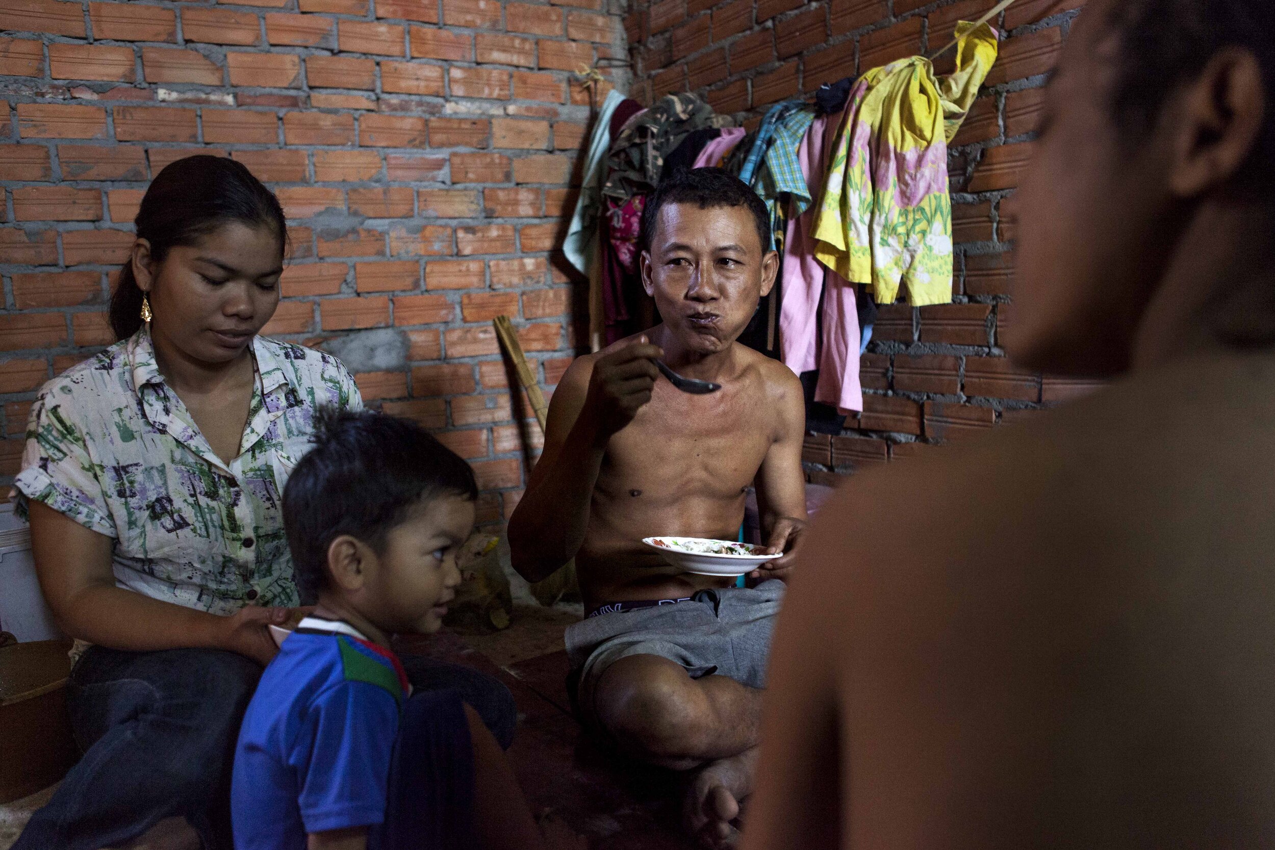  41 year old Khim Sarith eats breakfast with his family in one of the rooms on the building site they are living and working in. 