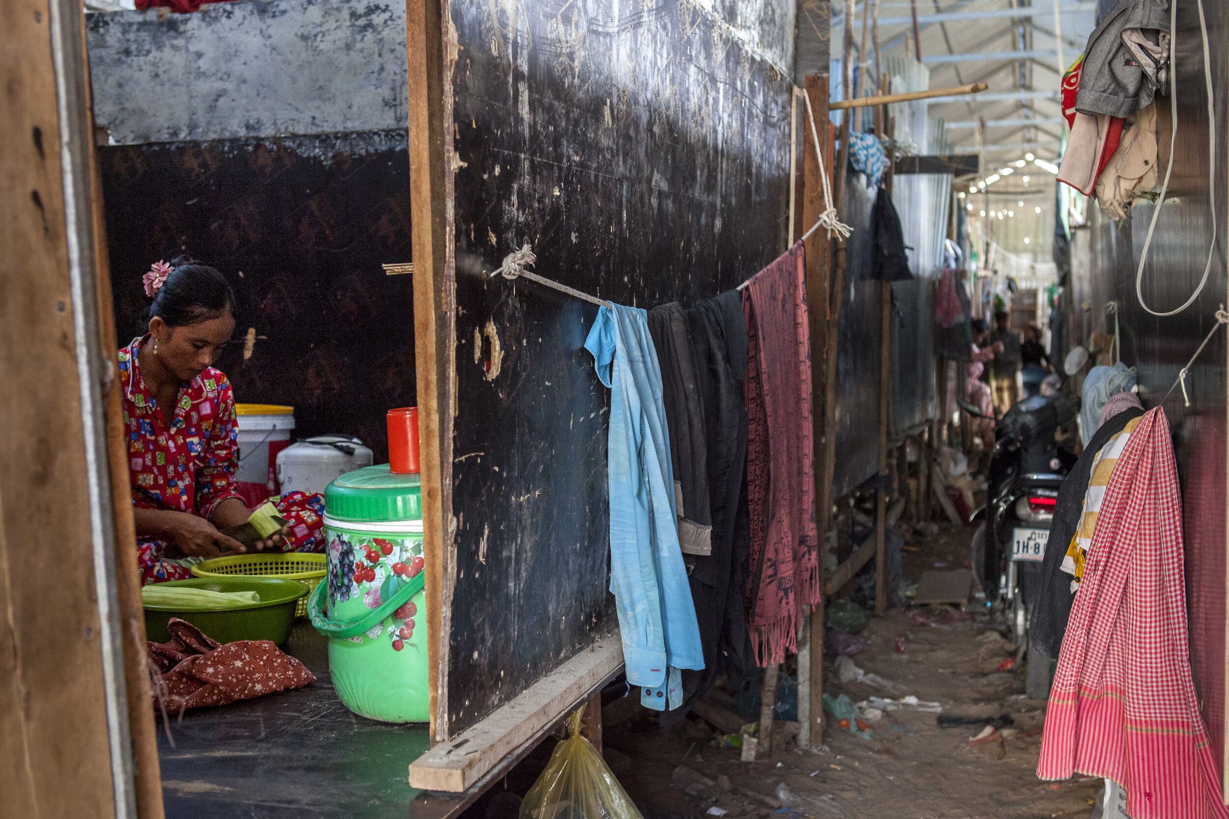  A woman prepares food in her home; a single room inside a shed provided by the construction company on the build site of the 'Phnom Penh City Centre' development. 