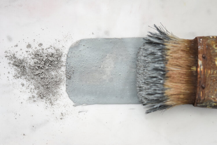 Aviary Milk Paint in powdered and liquid form on an antique paint brush