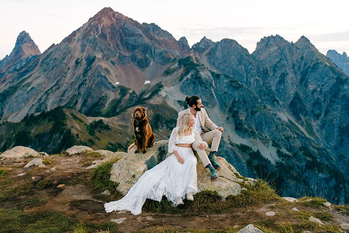 couple sitting on rock with their dog in wedding attire at Winchester mountain lookout