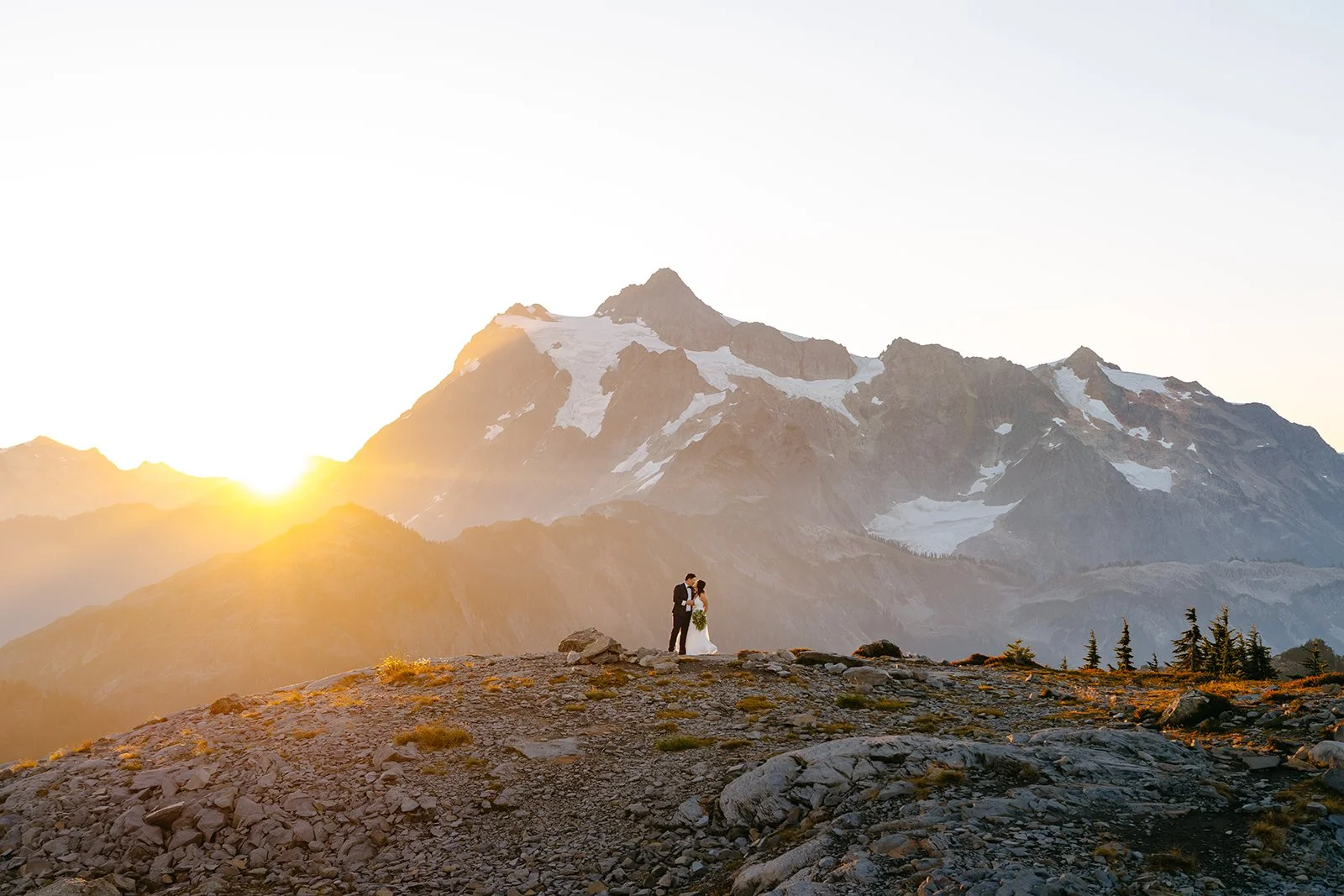 bride and groom kissing during sunrise in the north cascades with Mt Shuksan in the background