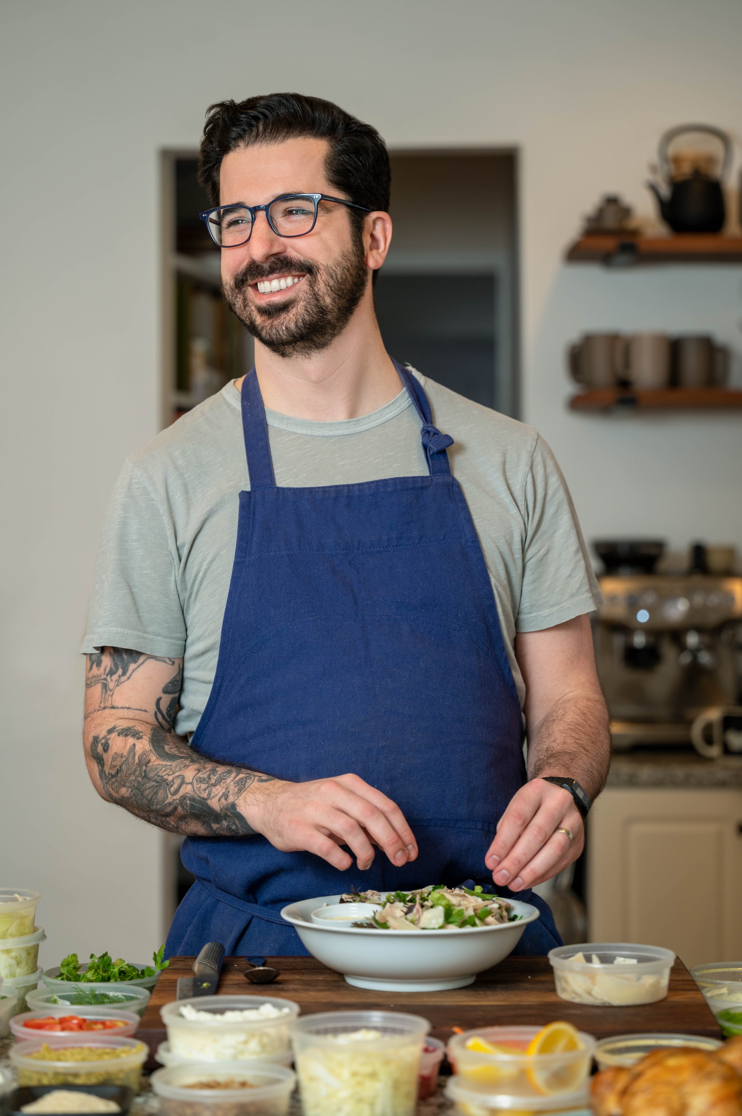 chef photo wearing blue apron looking off camera while preparing a salad