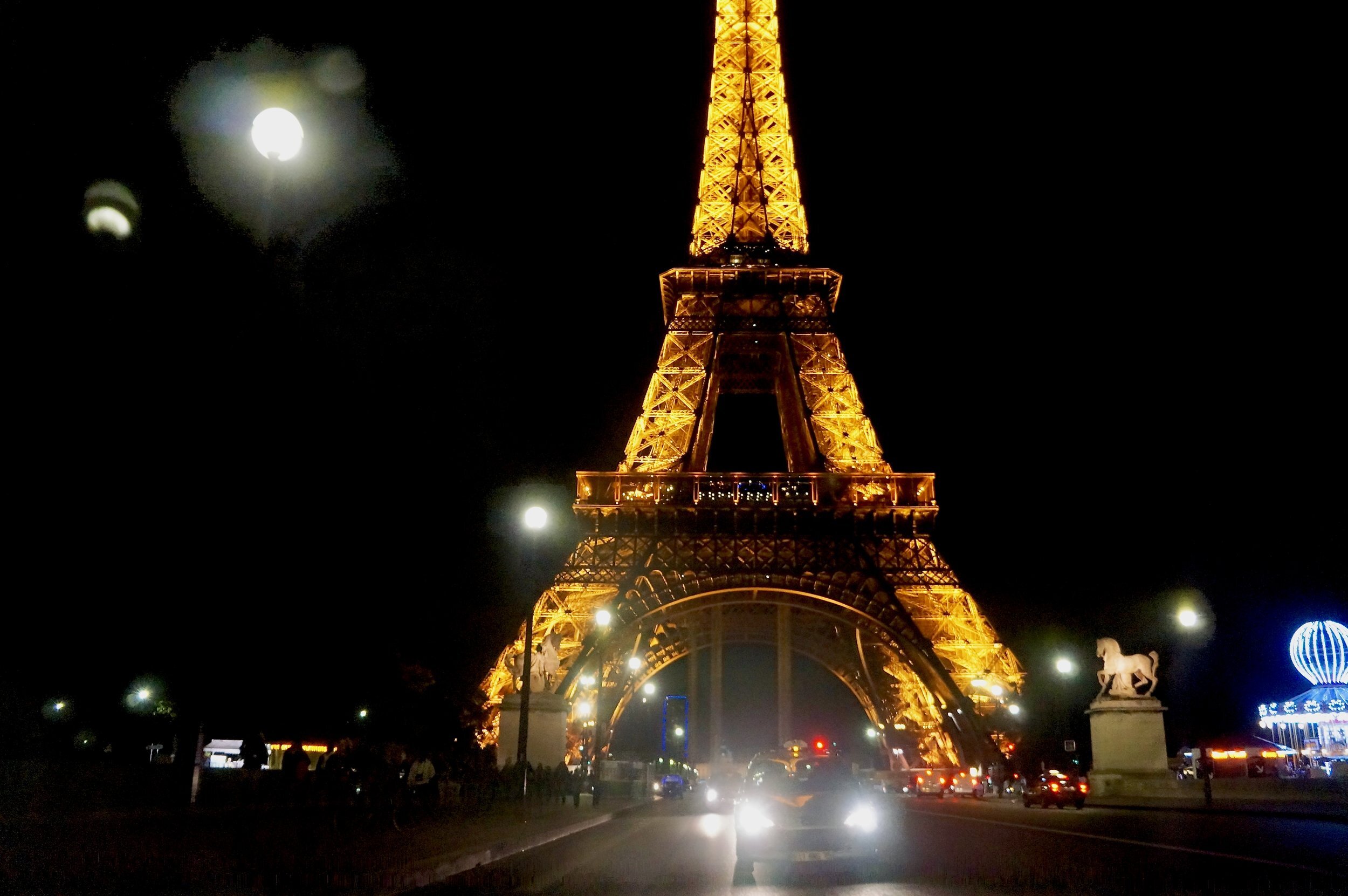 Eiffel Tower illuminated at night with cars and streetlights