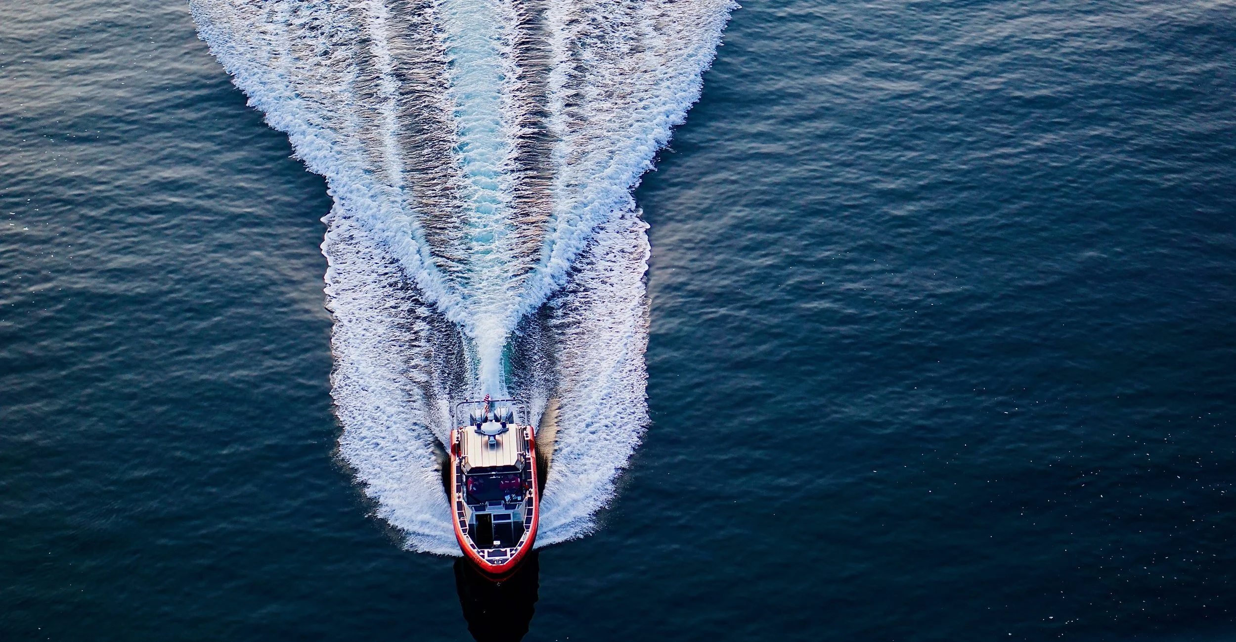 Aerial view of a speedboat creating a wake in the ocean.