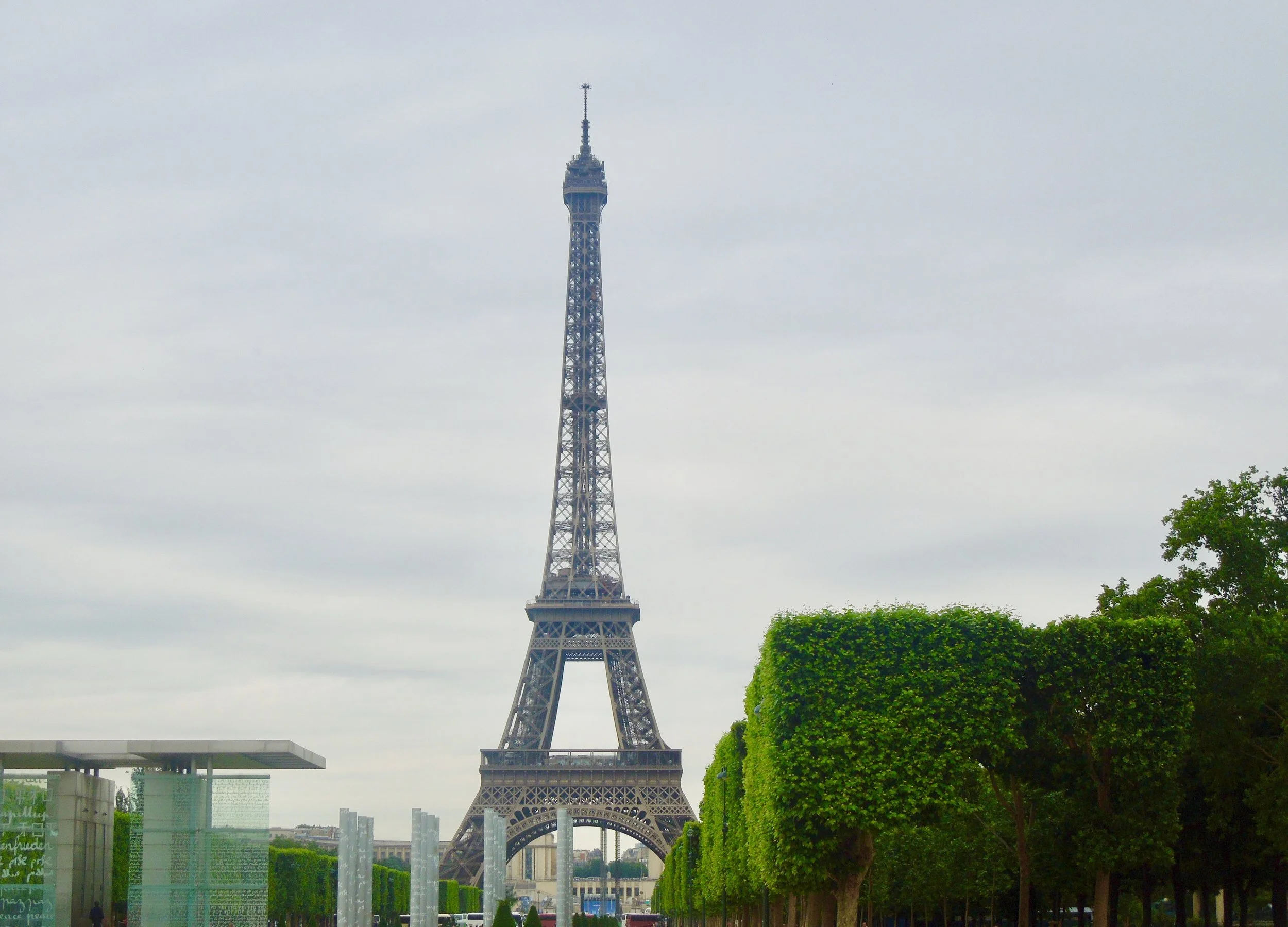 The Eiffel Tower with trees and glass art installations in the foreground.