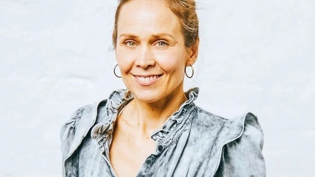 Heike Dittmers, Mindset Coach und Rapid Resoultion Therapy Specialsit mit grauem Oberteil und Ohrringen gegen einen hellen Hintergrund.