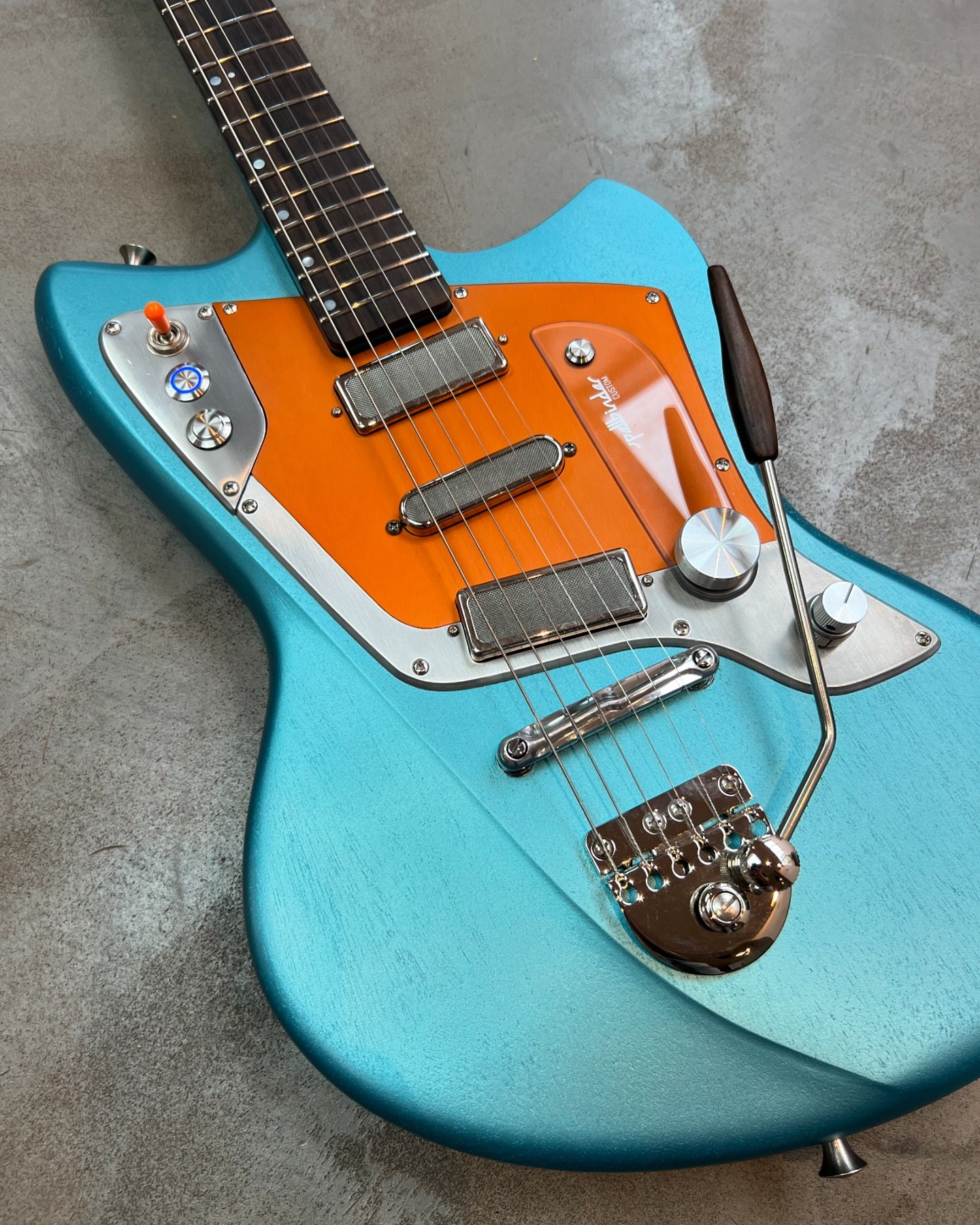 A rather tropical Spellbinder Custom in Cozumel Blue metallic for @marcokanzcine.

Open grain finish (and matching neck) with an orange anodised aluminium pickguard. Ziricote fingerboard and matching bespoke trem tip. Hipshot knurled tuners on a reve