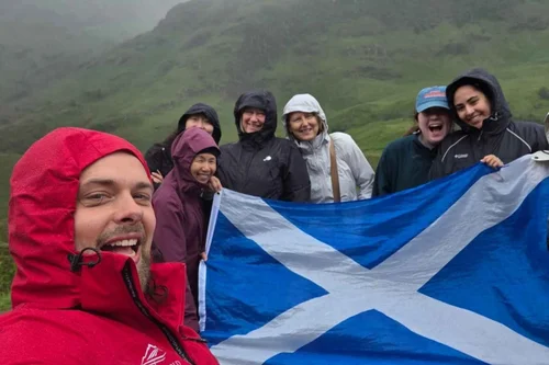 A Scotland's Wild guide and group with a Saltire in the rain at Glencoe