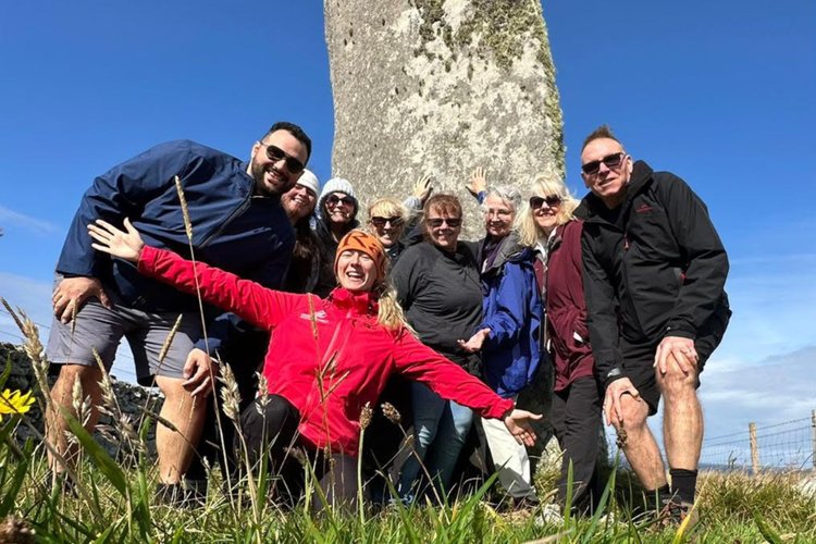 Scotland's Wild guide Rachel with tour guests beside standing stones