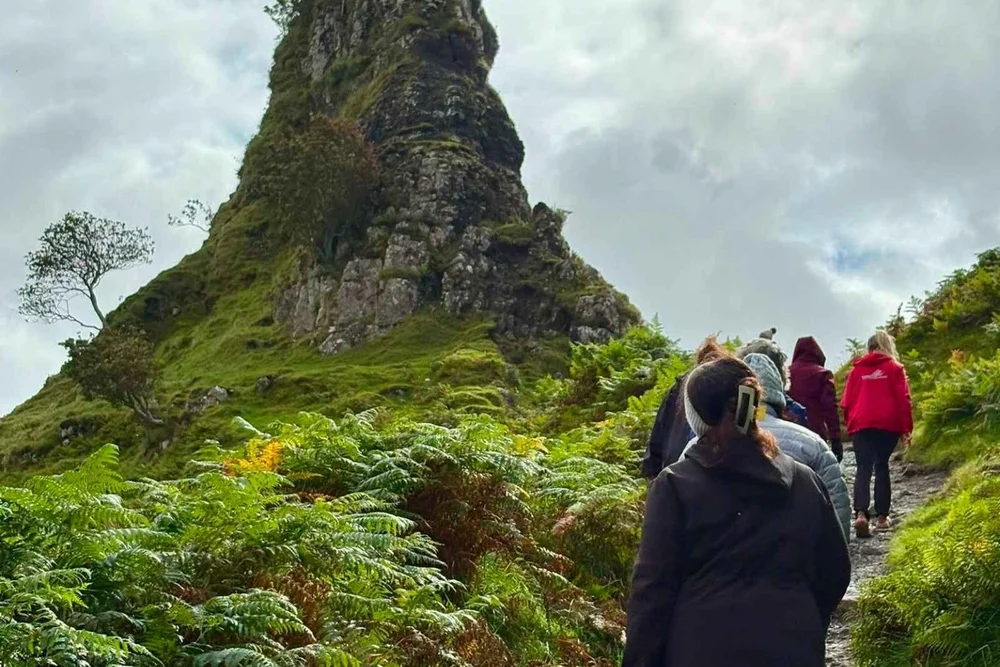 A small group walking the green hills of the Fairy Glen on Skye