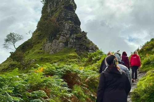 A small group walking the green hills of the Fairy Glen on Skye