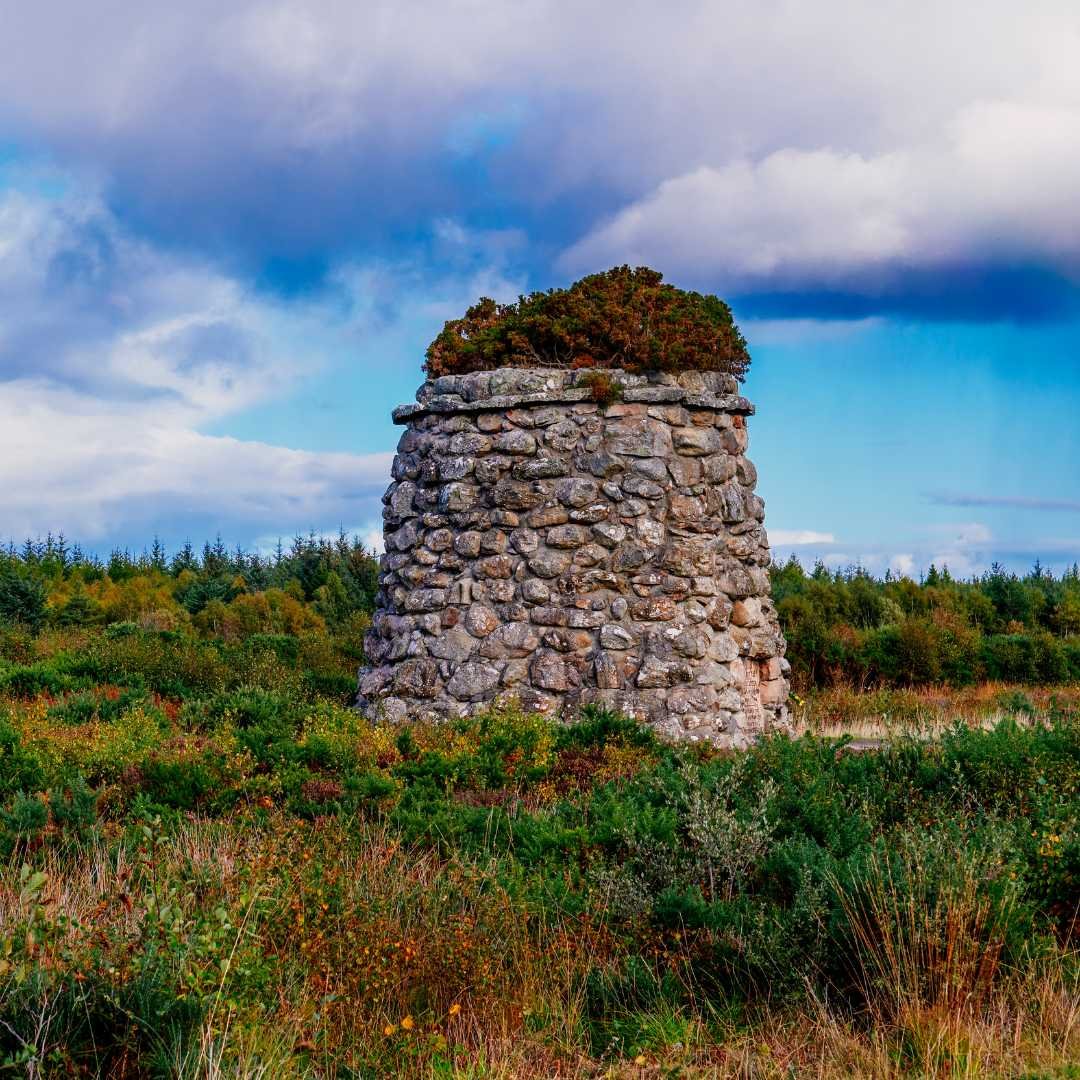 Memorial cairn standing on Culloden Battlefield beneath a dramatic Highland sky