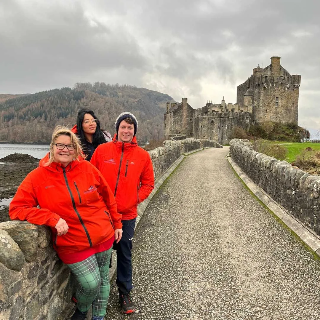 Visitors wearing waterproof jackets beside Eilean Donan Castle