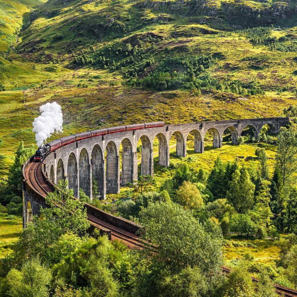 A steam train crossing the curved Glenfinnan Viaduct in the West Highlands