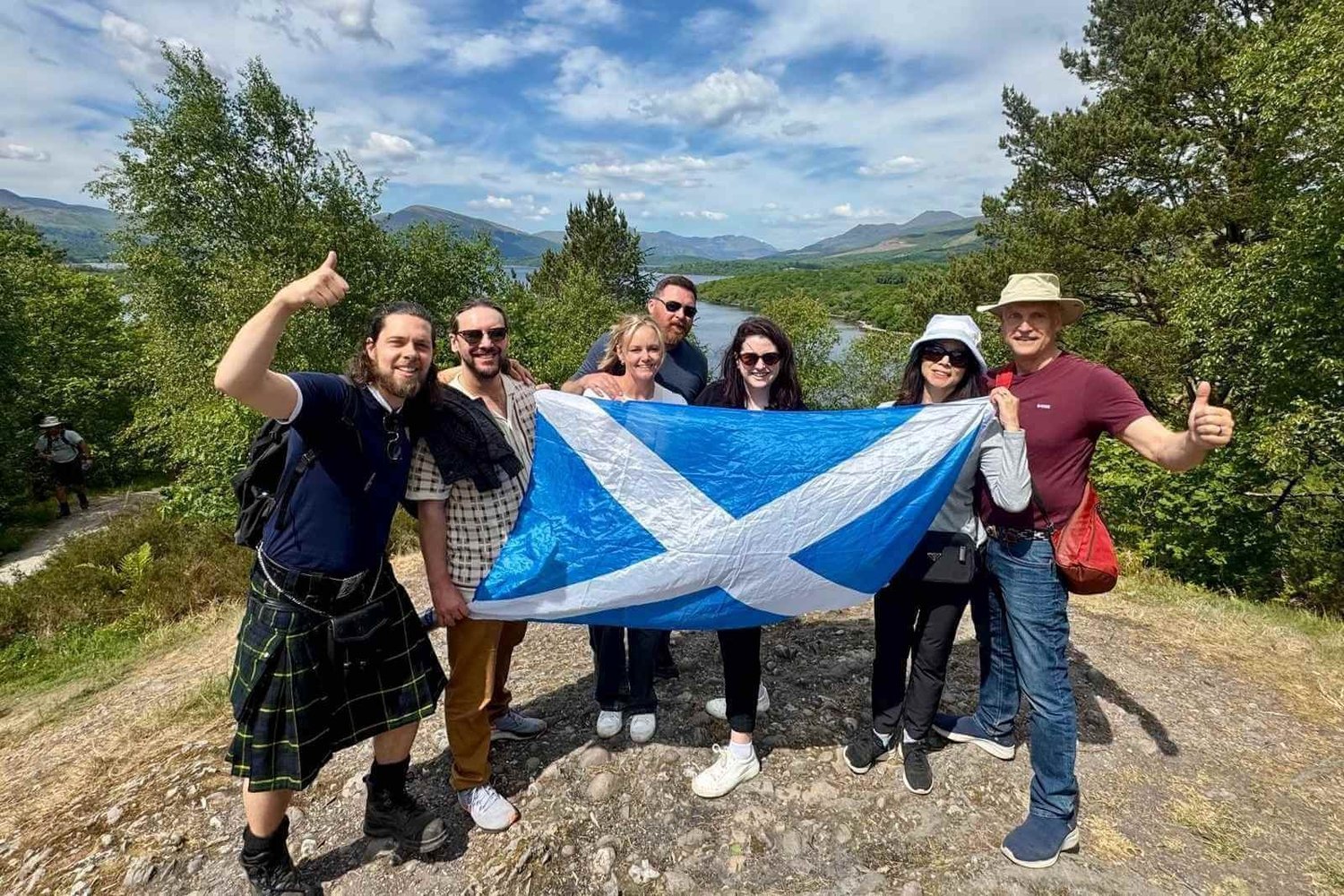 A Scotland’s Wild guide and guests holding a Scottish flag above Loch Lomond