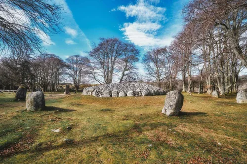 Standing stones around a Bronze Age burial cairn at Clava Cairns, ringed by trees