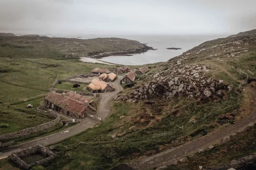 An aerial view of a blackhouse village by the sea