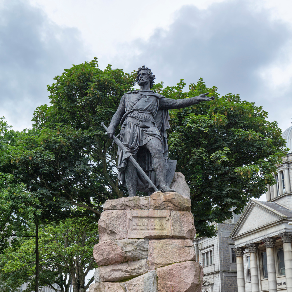 A statue of William Wallace with his arm outstretched, on a granite plinth