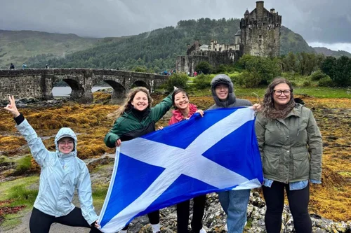 A tour group with a Saltire in front of Eilean Donan Castle