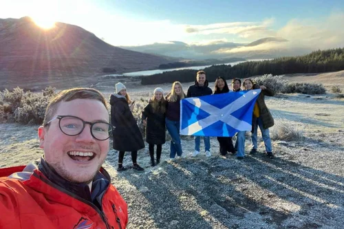 Guide Andrew and a group with a Saltire in snowy Glencoe