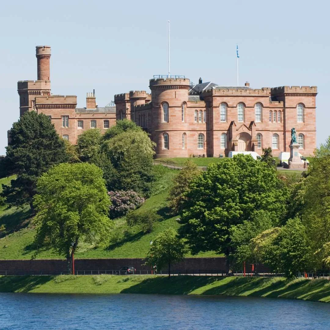 The red sandstone Inverness Castle above trees in the city centre