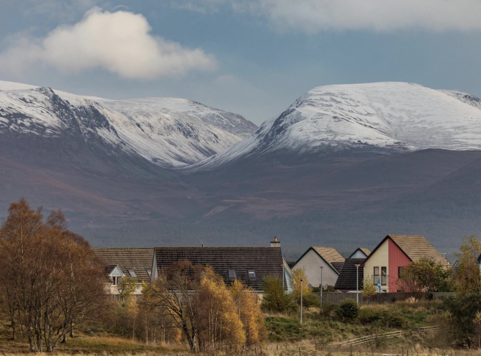 Snow-covered Cairngorm mountains rising behind houses near Aviemore
