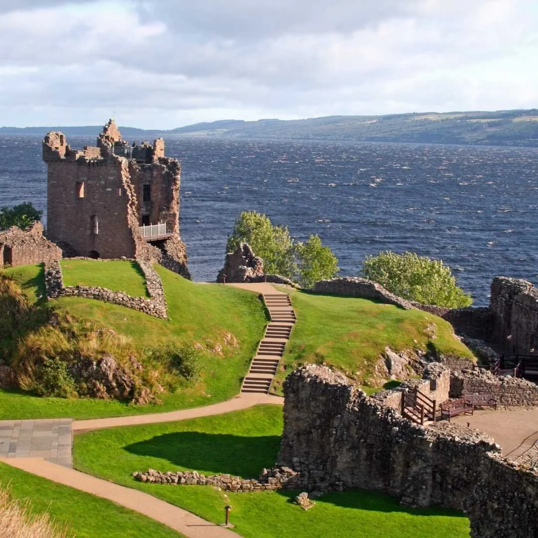 Ruins of Urquhart Castle overlooking the dark water of Loch Ness