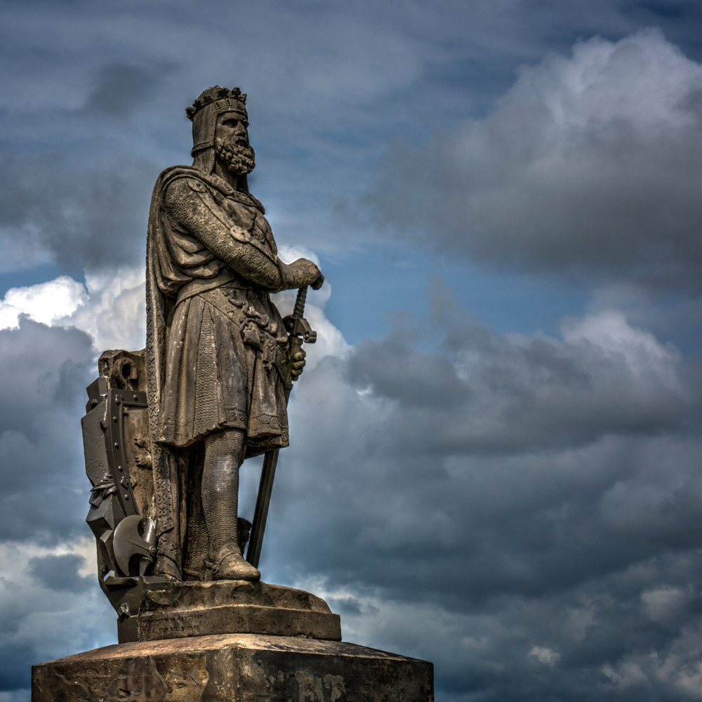 A stone statue of Robert the Bruce wearing a crown and holding a shield