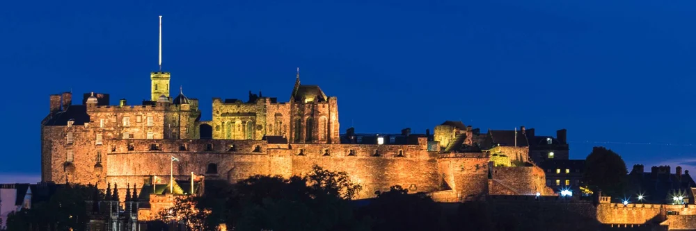 Edinburgh Castle lit up at night on Castle Rock above the city