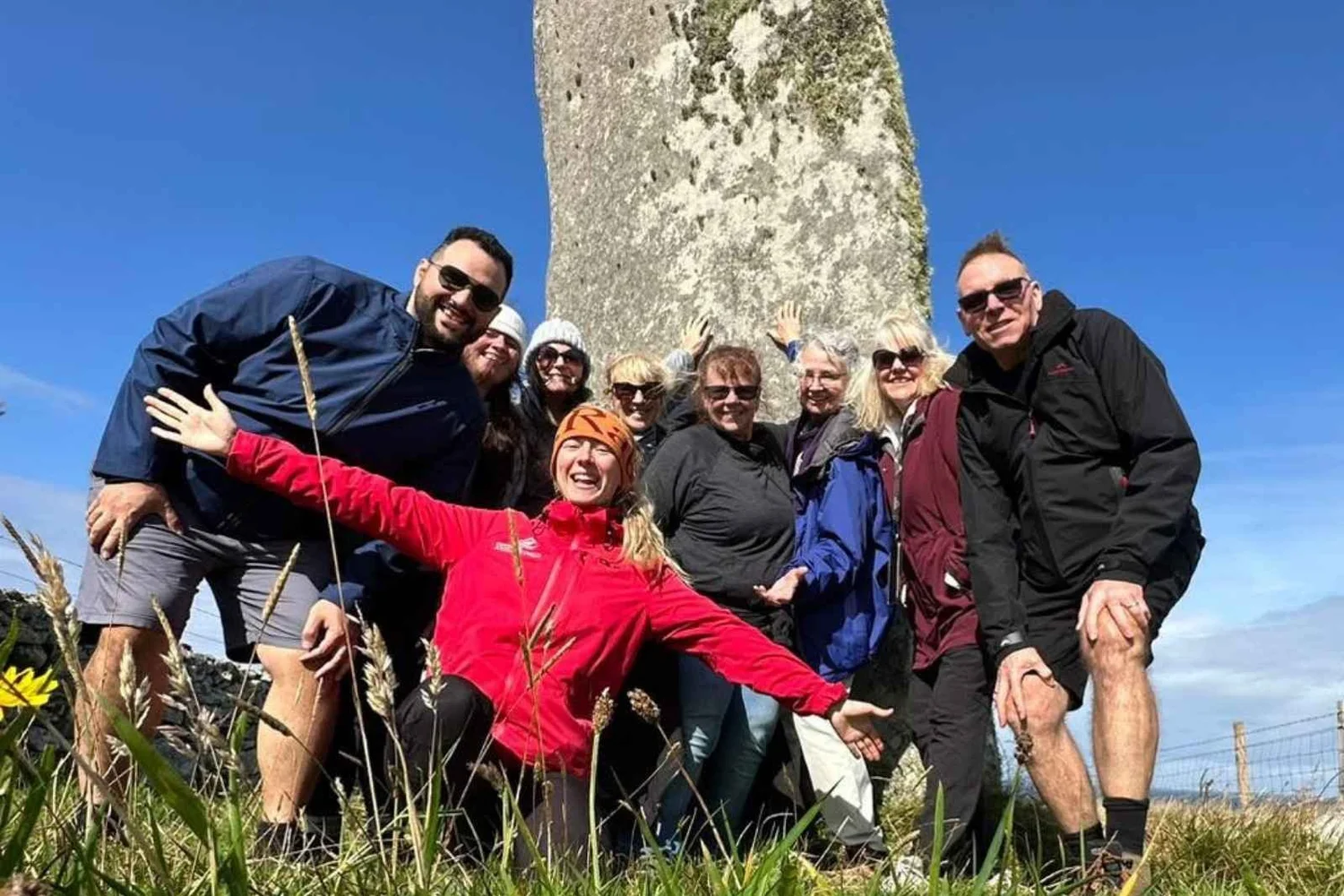 Scotland's Wild guide Rachel and her small group laughing in front of a standing stone
