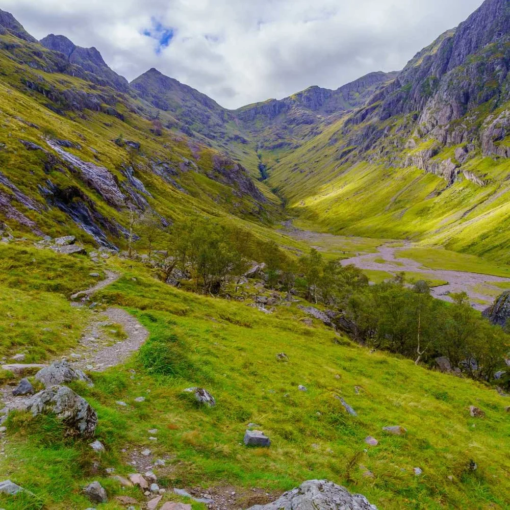 The grassy floor of the Lost Valley surrounded by the mountains of Glencoe